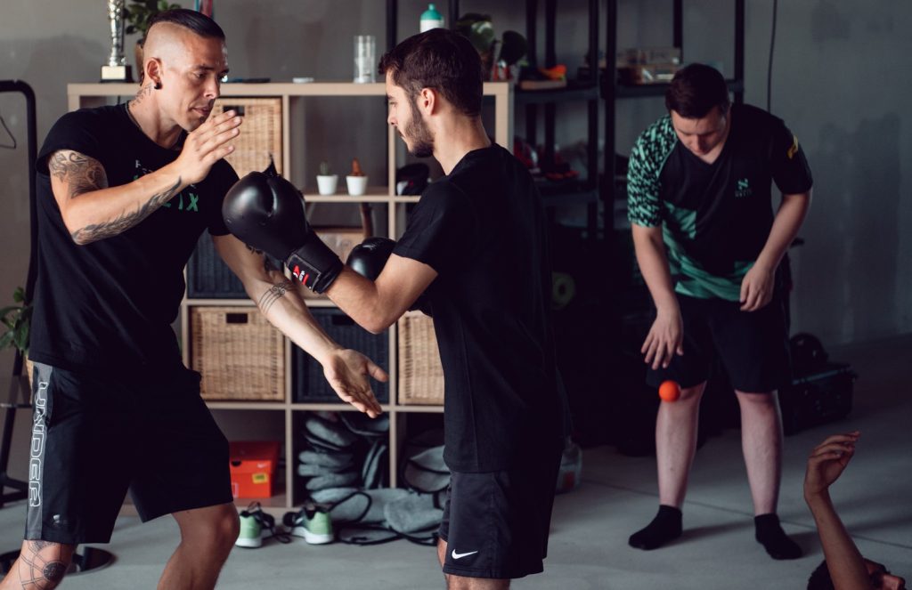 Esports-Athlet trainiert mit Coach körperlich mit Boxhandschuhen